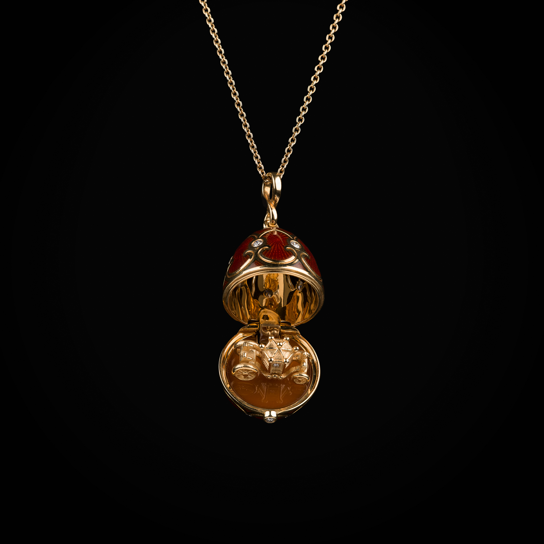 Cadena con dije huevo con esmalte guiloché vitreo rojo interior con carroza sobre plataforma de cornalina de oro amarillo 18k con diamantes naturales